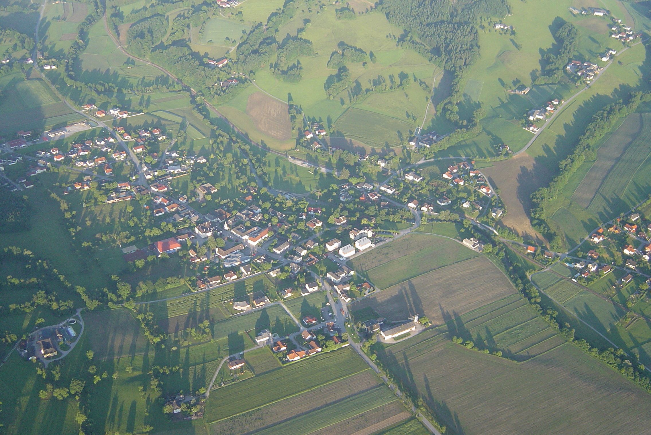 Aerial view of a small village with surrounding fields and forests.