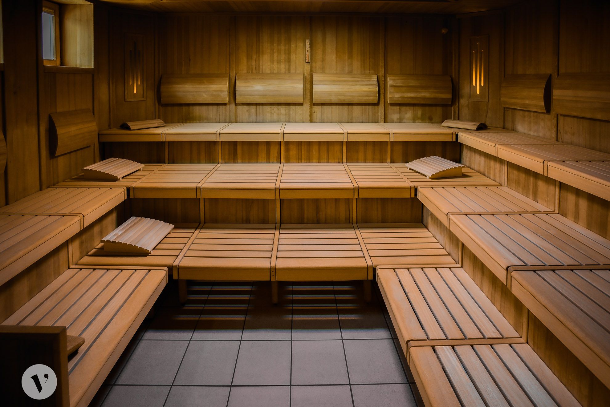 Interior view of an empty wooden sauna with several rows of seats and headrests.