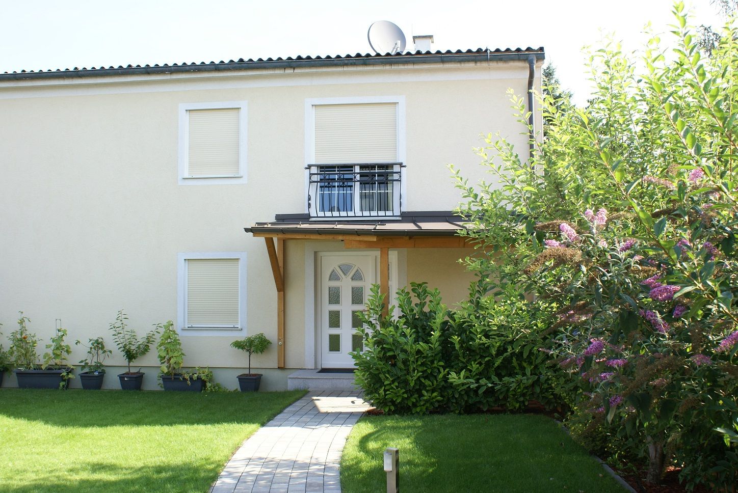 Exterior view of a two-story house with garden and plants.