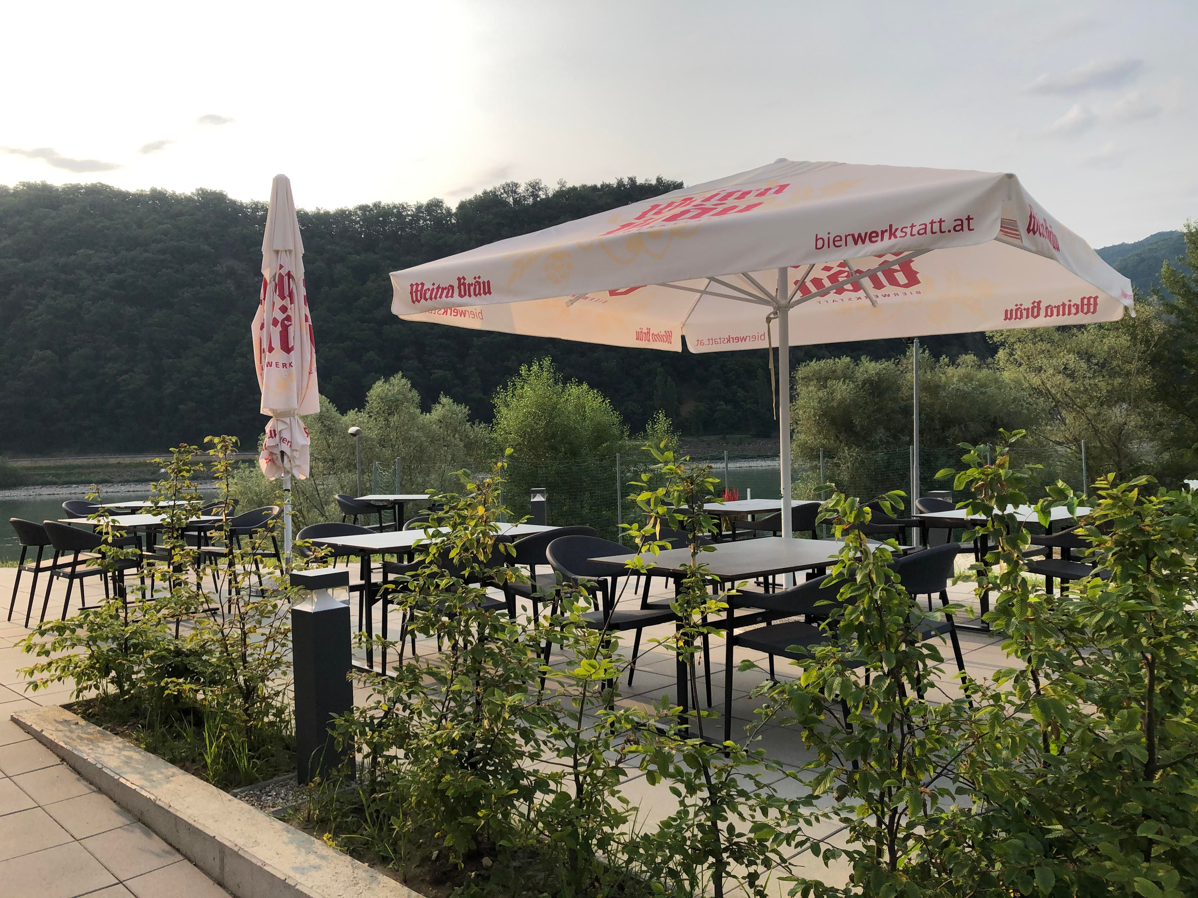 Terrace with tables, chairs and parasols, surrounded by nature.