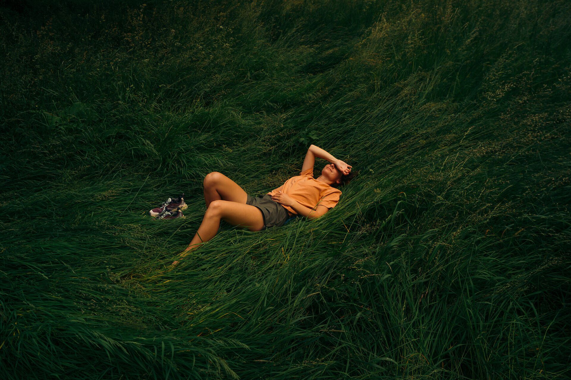 A woman lies in the middle of a meadow surrounded by tall grass and takes a break