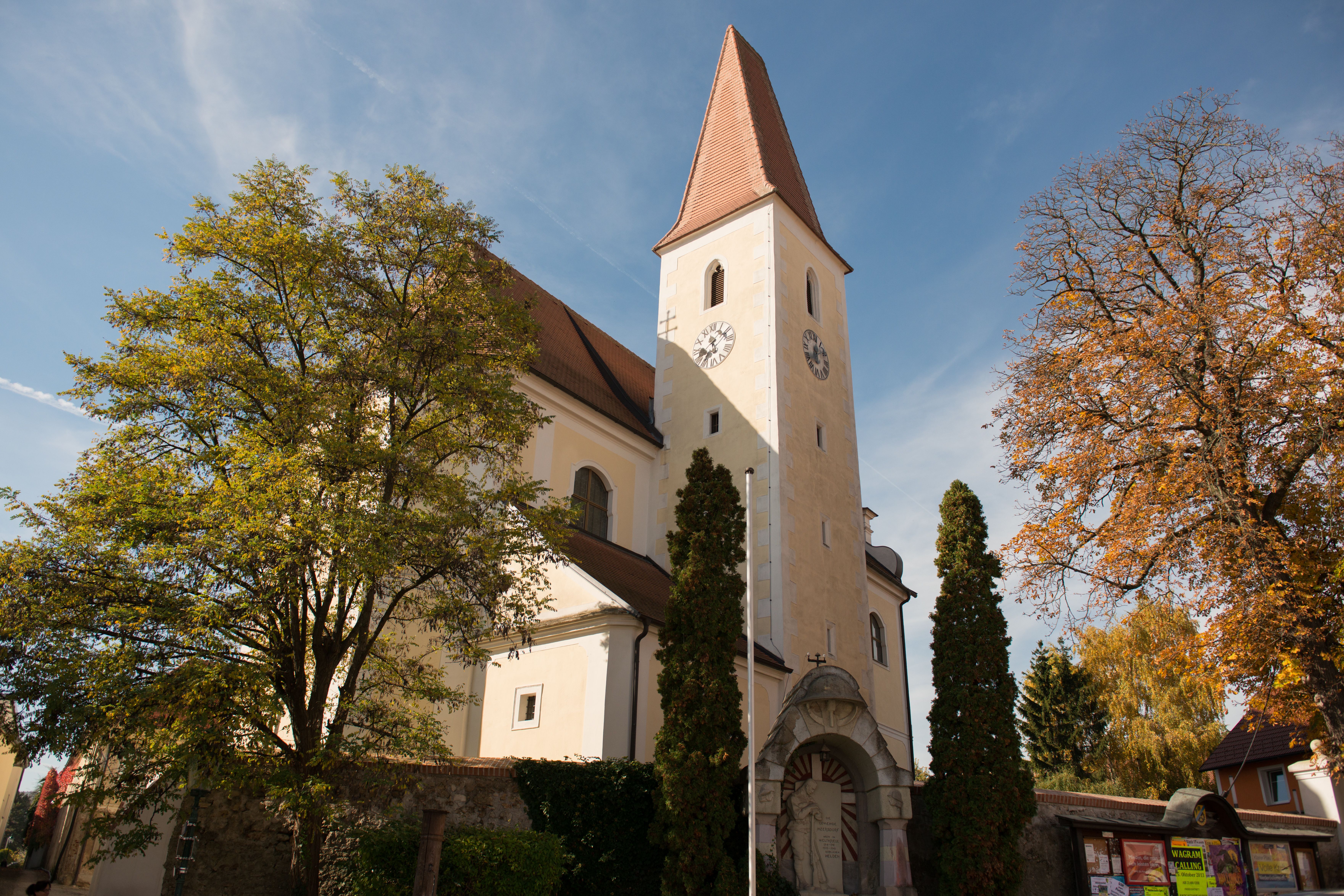 Church with tower and clock, surrounded by trees in the fall.