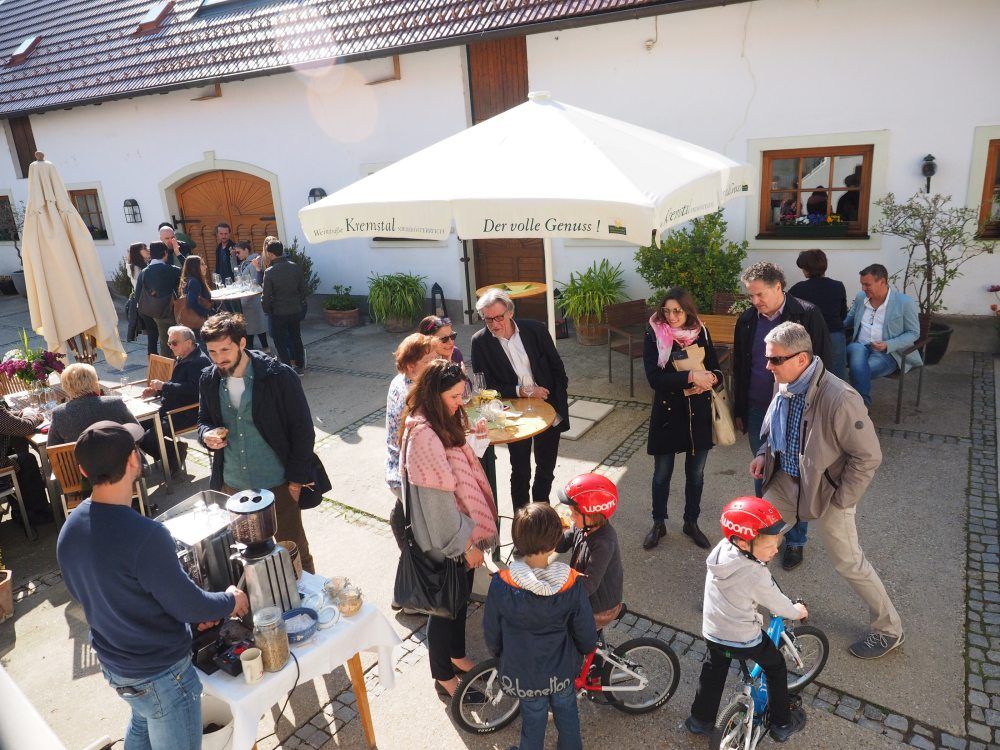People at a spring festival in a courtyard with a parasol and drinks.