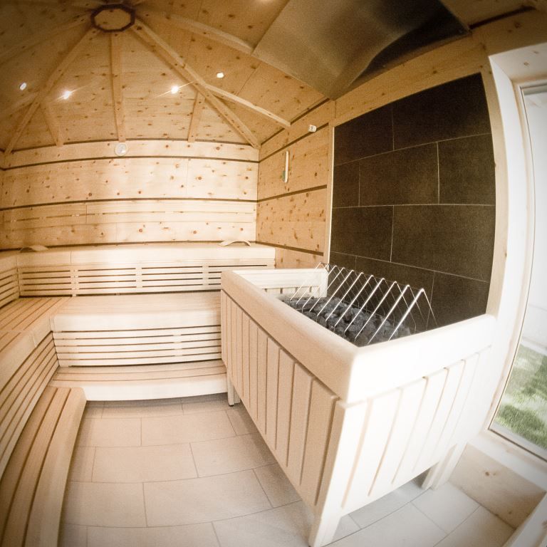 Interior view of a modern sauna with wooden benches and stove.