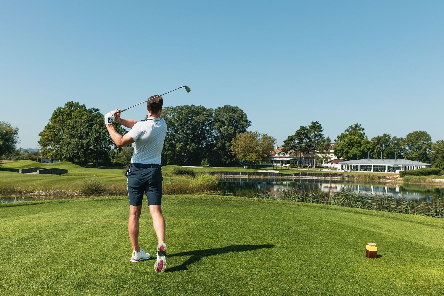 Golfer with golf club in hand, playing golf.