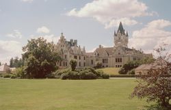 Grafenegg Castle with extensive lawn and trees in the foreground.