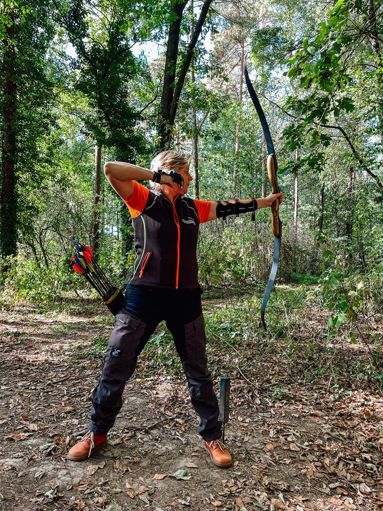 Person archery in the forest with bow and arrow.