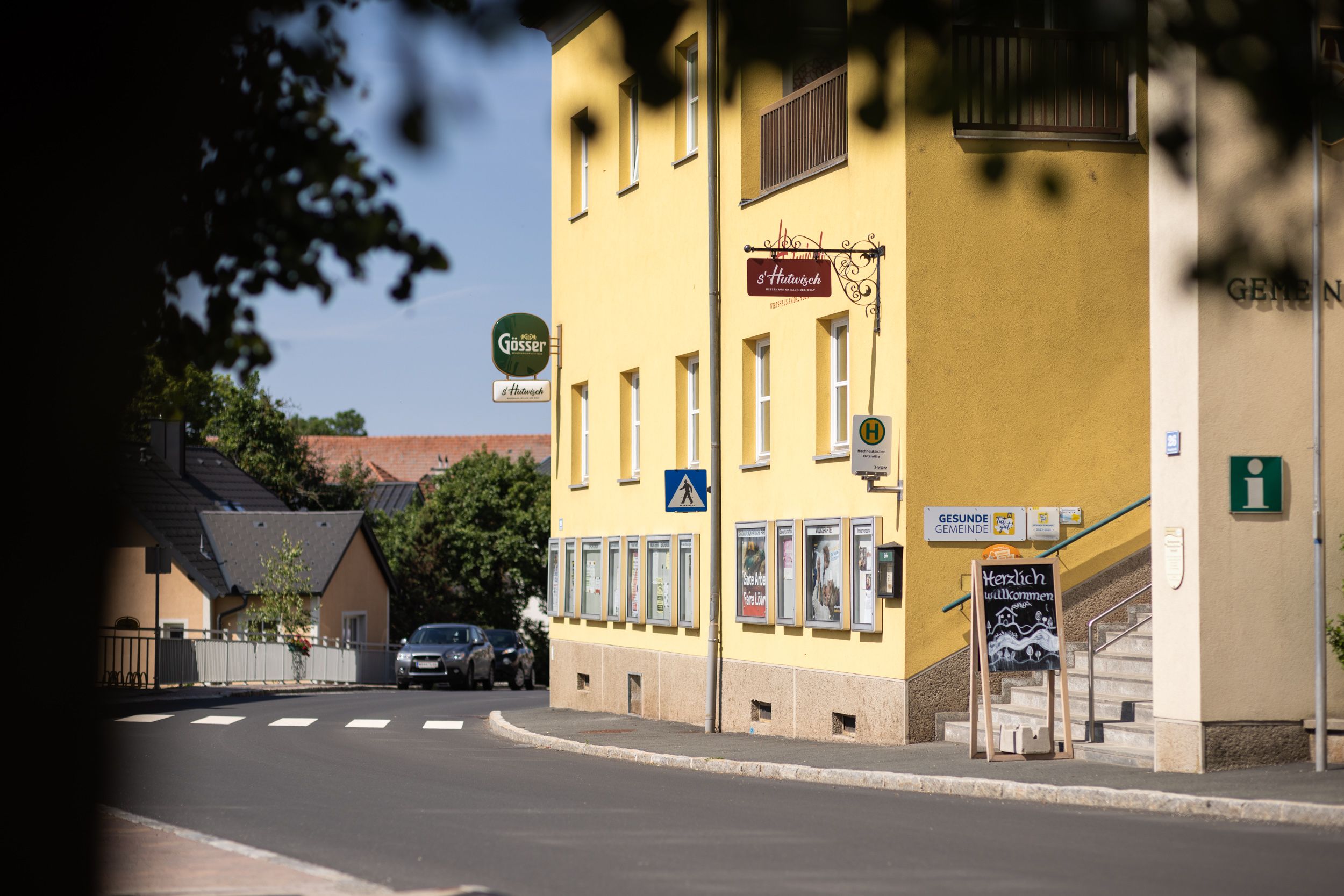 Yellow building next to road and crosswalk, with steps and s'Hutwisch sign.