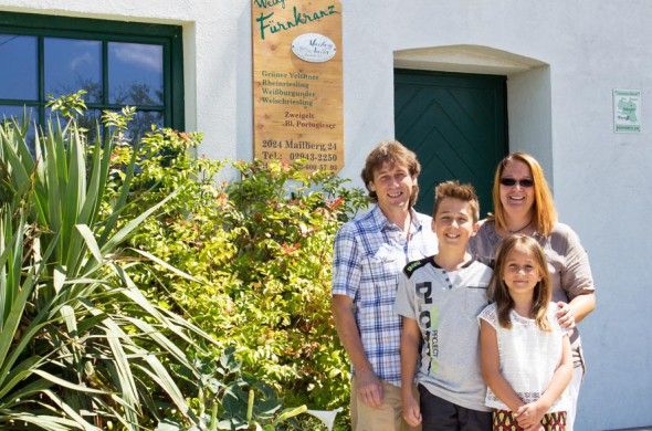 A family stands in front of a building with a sign for the Fürnkranz winery.