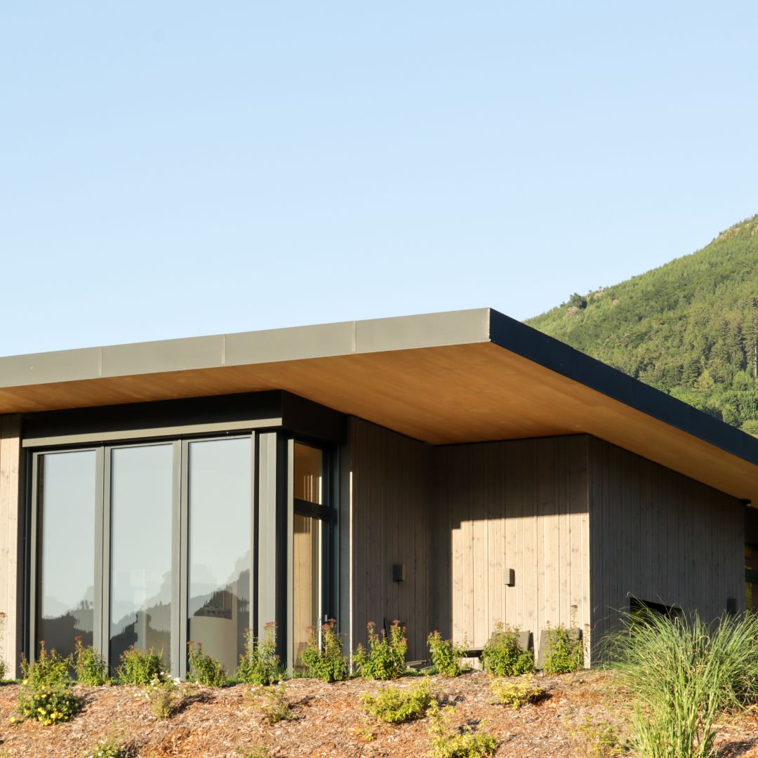 Modern lodge with flat roof and large windows, surrounded by green countryside.