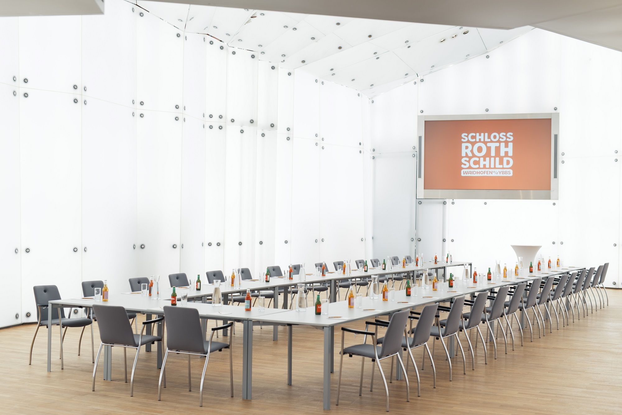Modern conference room in Schloss Rothschild with long tables, chairs and drinks.