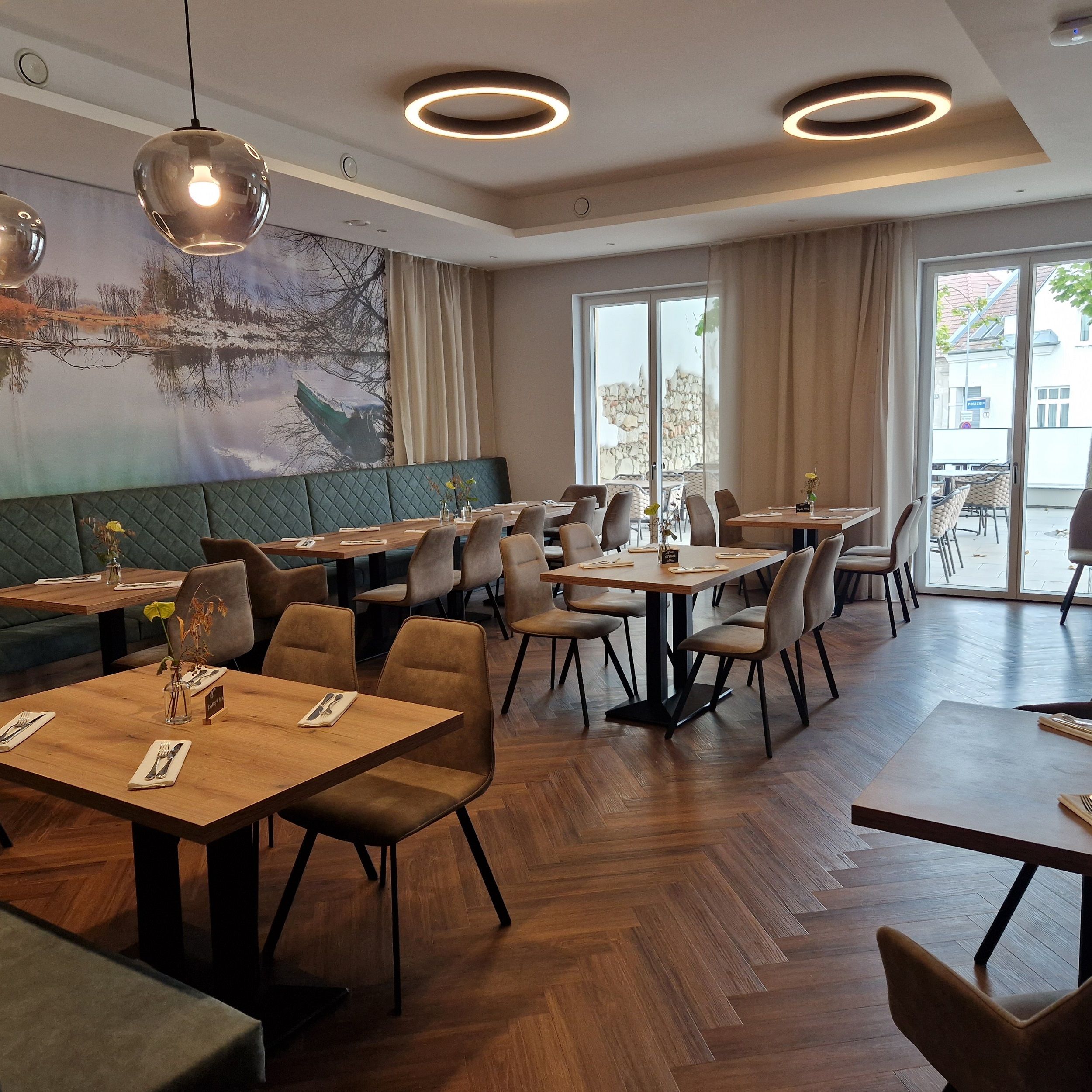Interior view of a modern restaurant with wooden floor, tables and chairs.