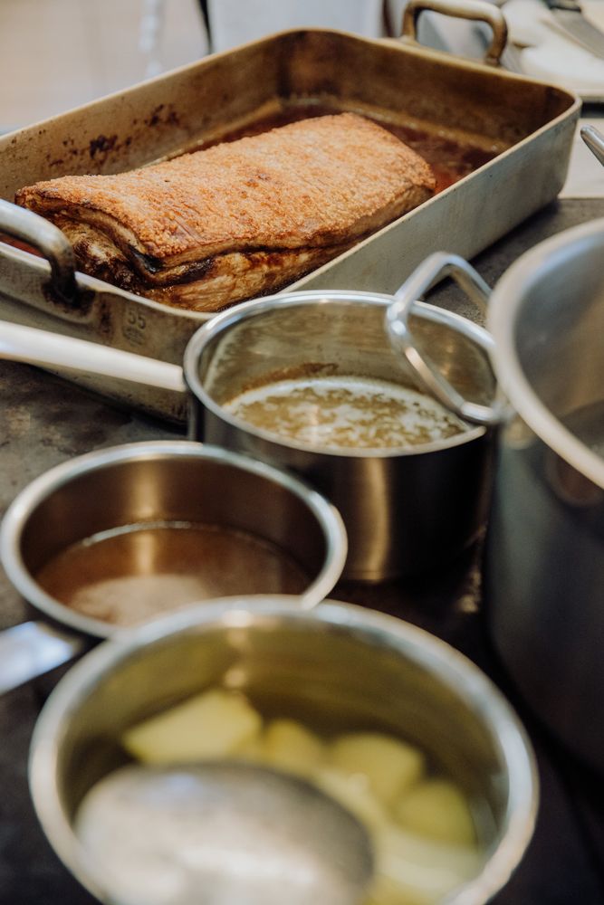 Roast in a casserole dish with pots on a stove in the kitchen.