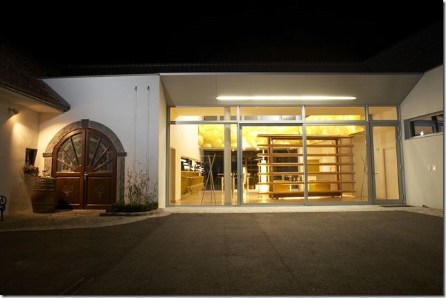 Modern building of a winery at night with illuminated interior.