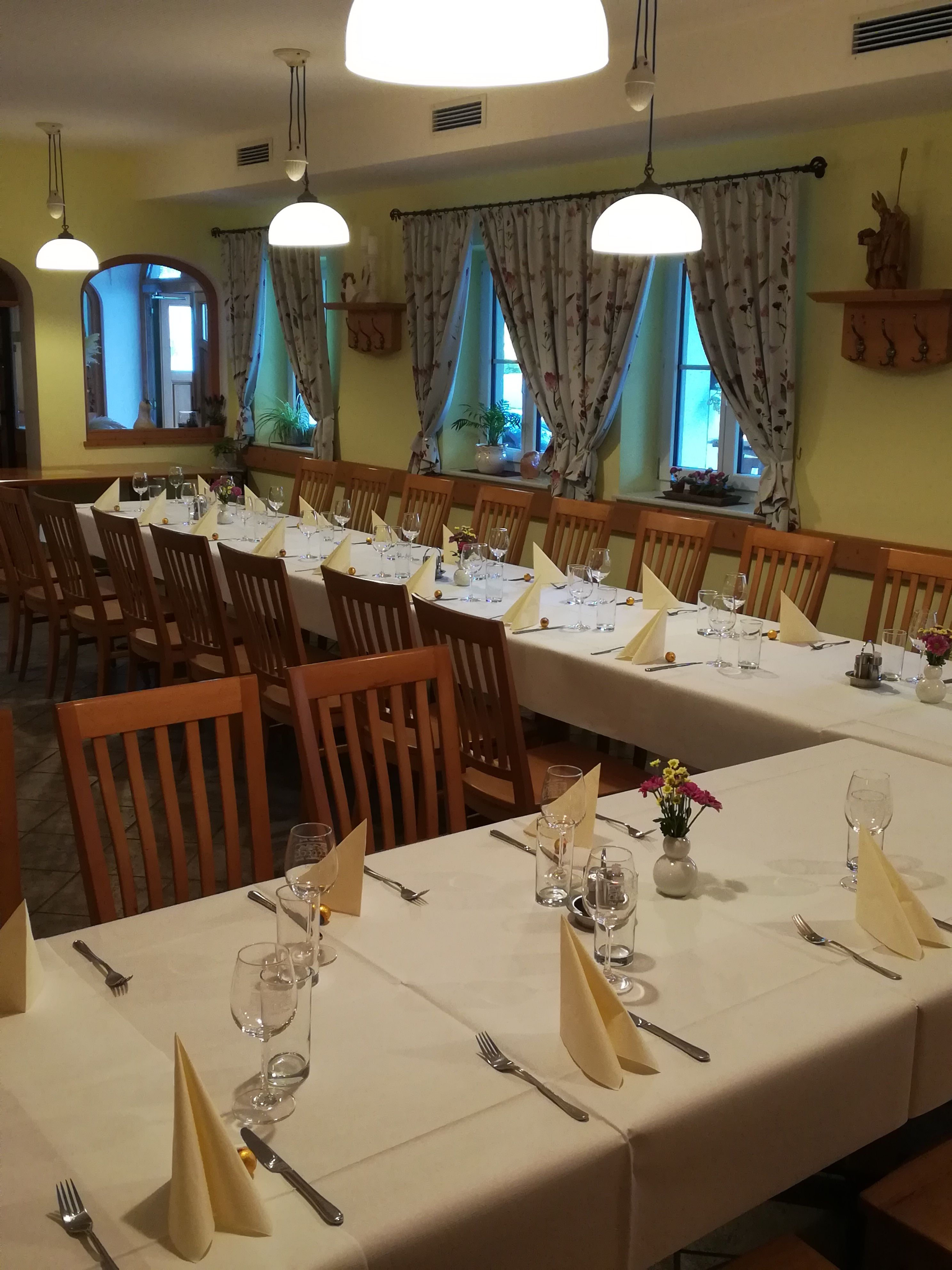 A festively decorated hall with long tables, chairs and decorative curtains.