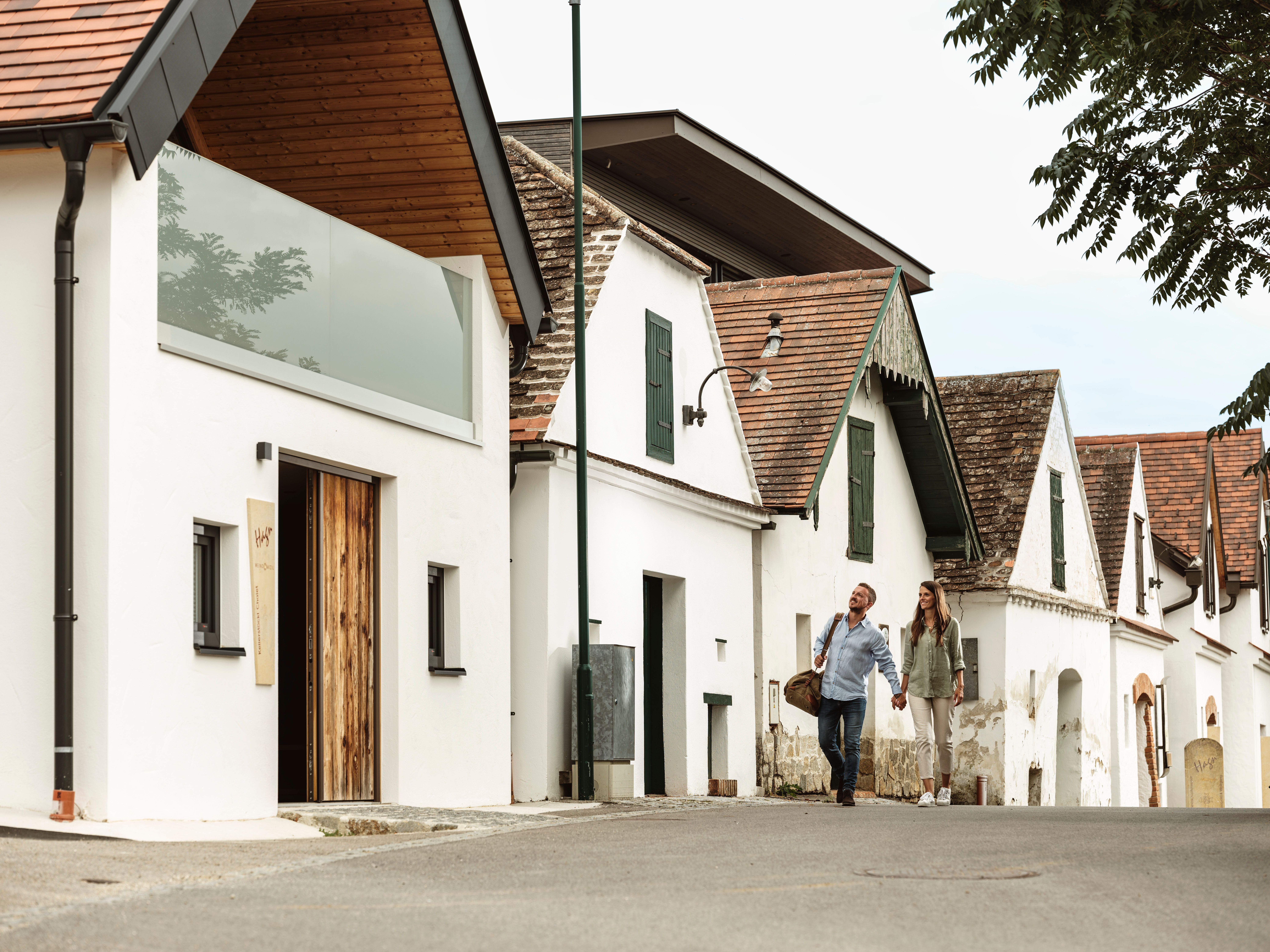A couple strolls past traditional wine cellars.