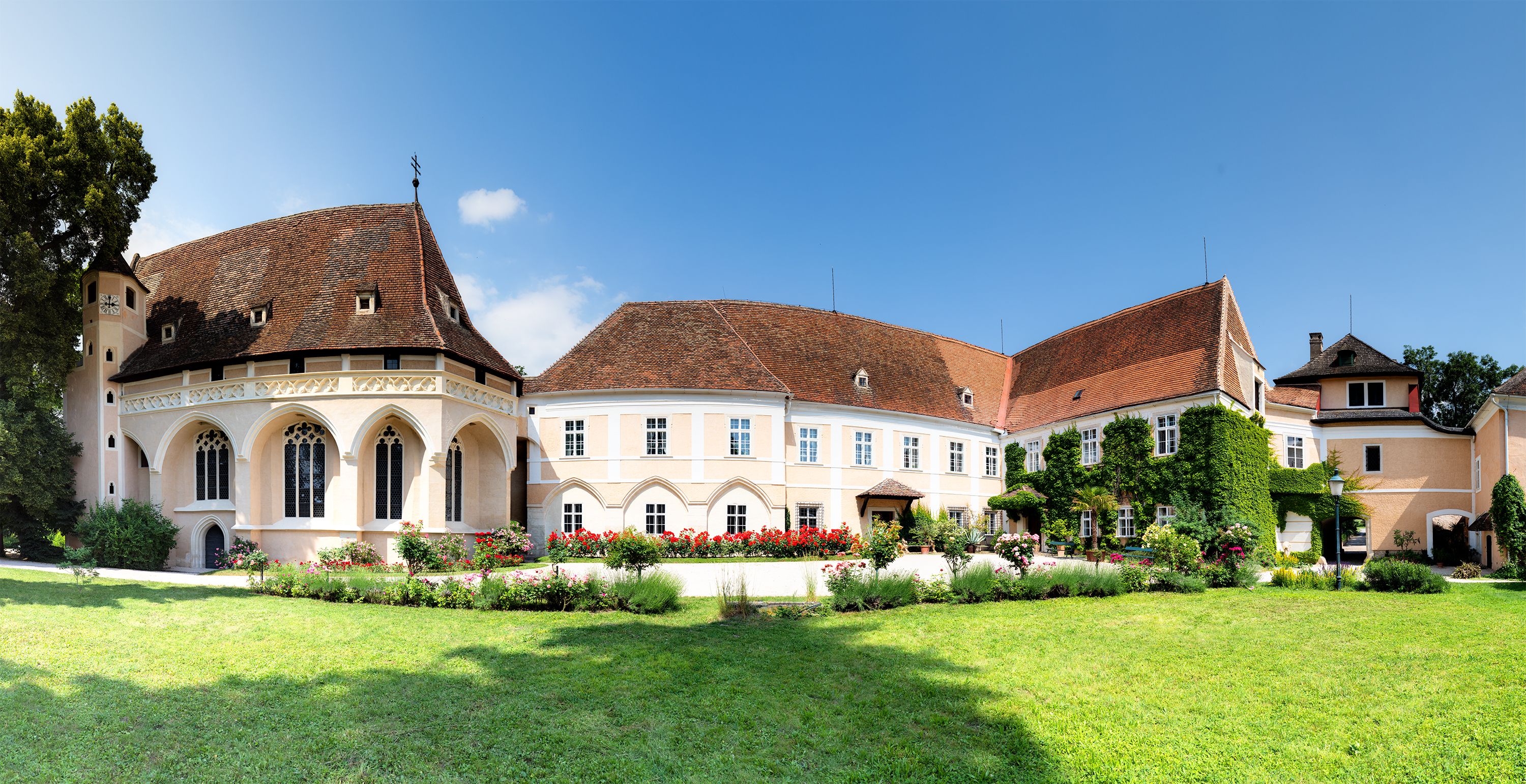 Panoramic view of Schrattenthal Castle with well-tended garden and blooming roses in the foreground.