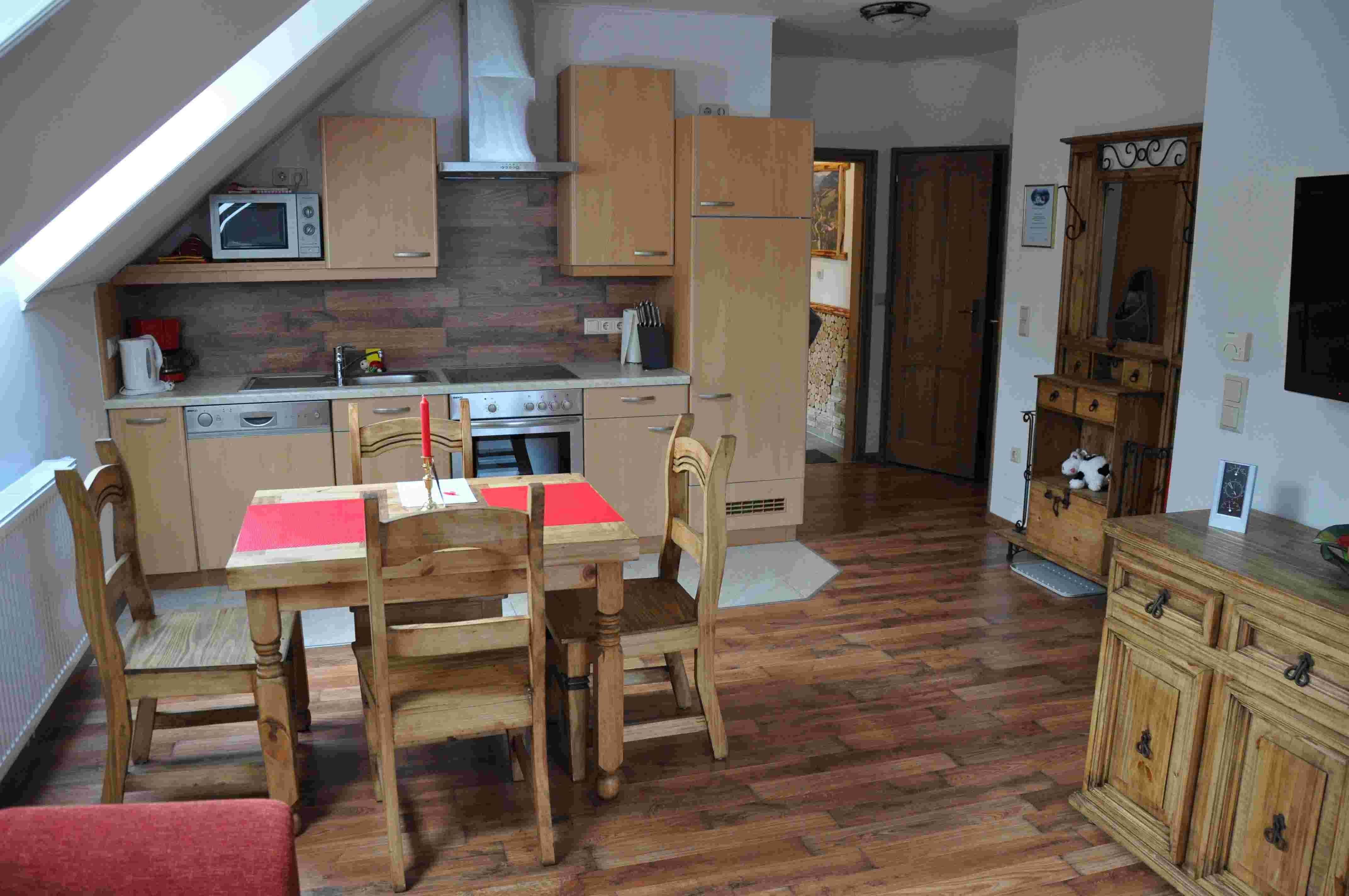 Cozy vacation apartment kitchen with wooden furniture and dining table.