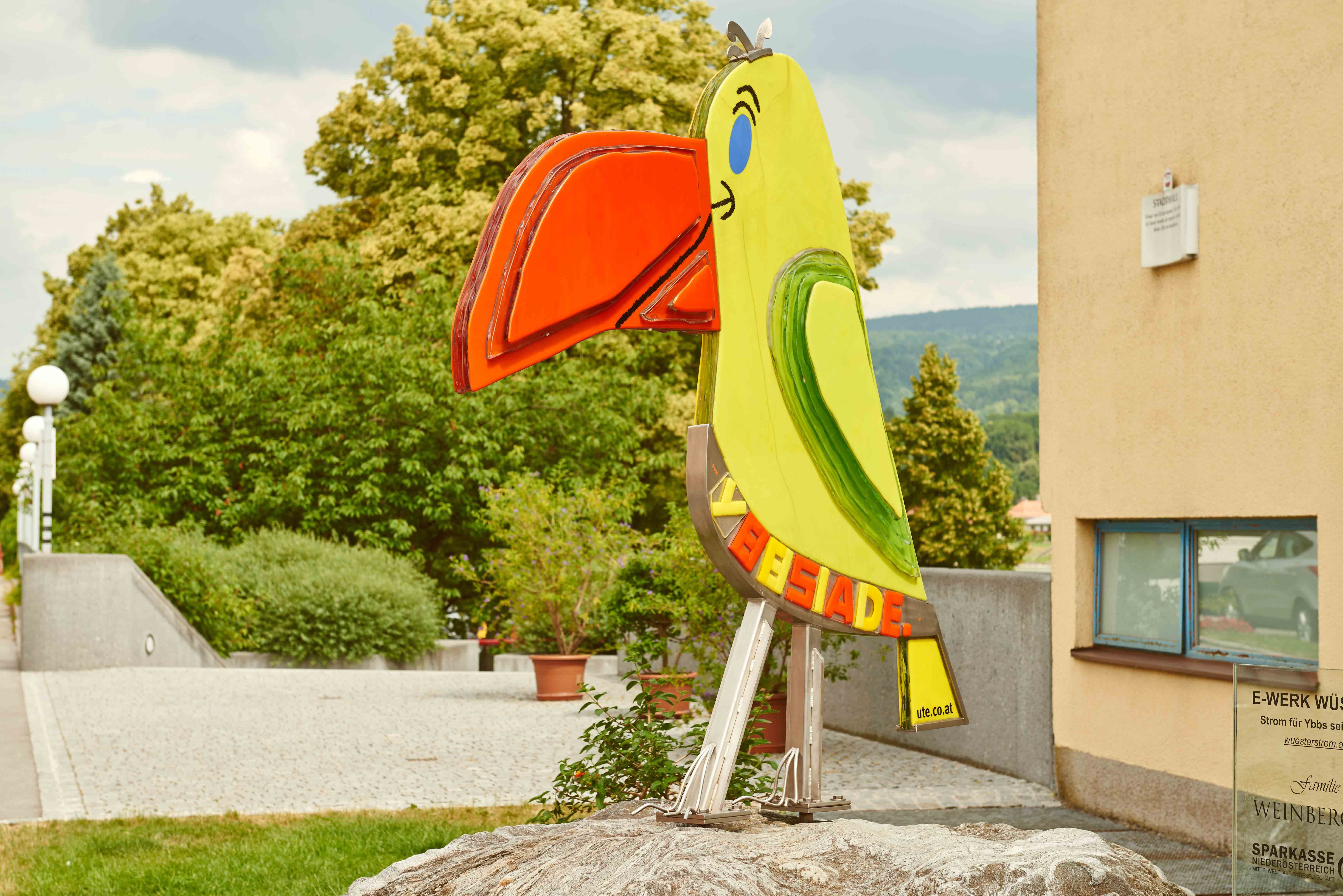 Colorful parrot statue in an urban environment.