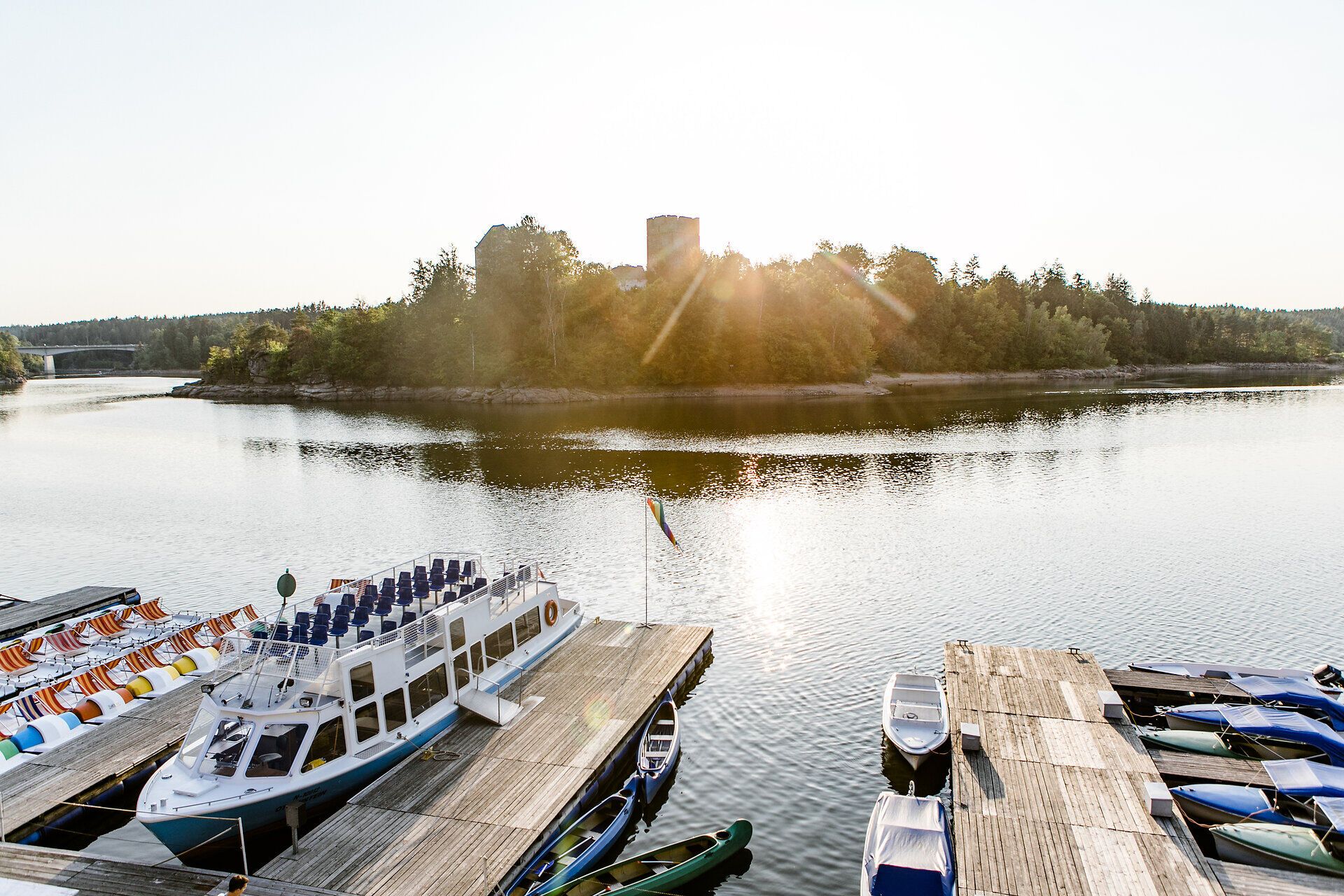 The Ottenstein Reservoir glistens in the warm summer sun, while gentle waves lap at the shore. Surrounded by lush greenery and majestic trees, the idyllic landscape invites visitors to enjoy boat trips and relaxing moments by the water.