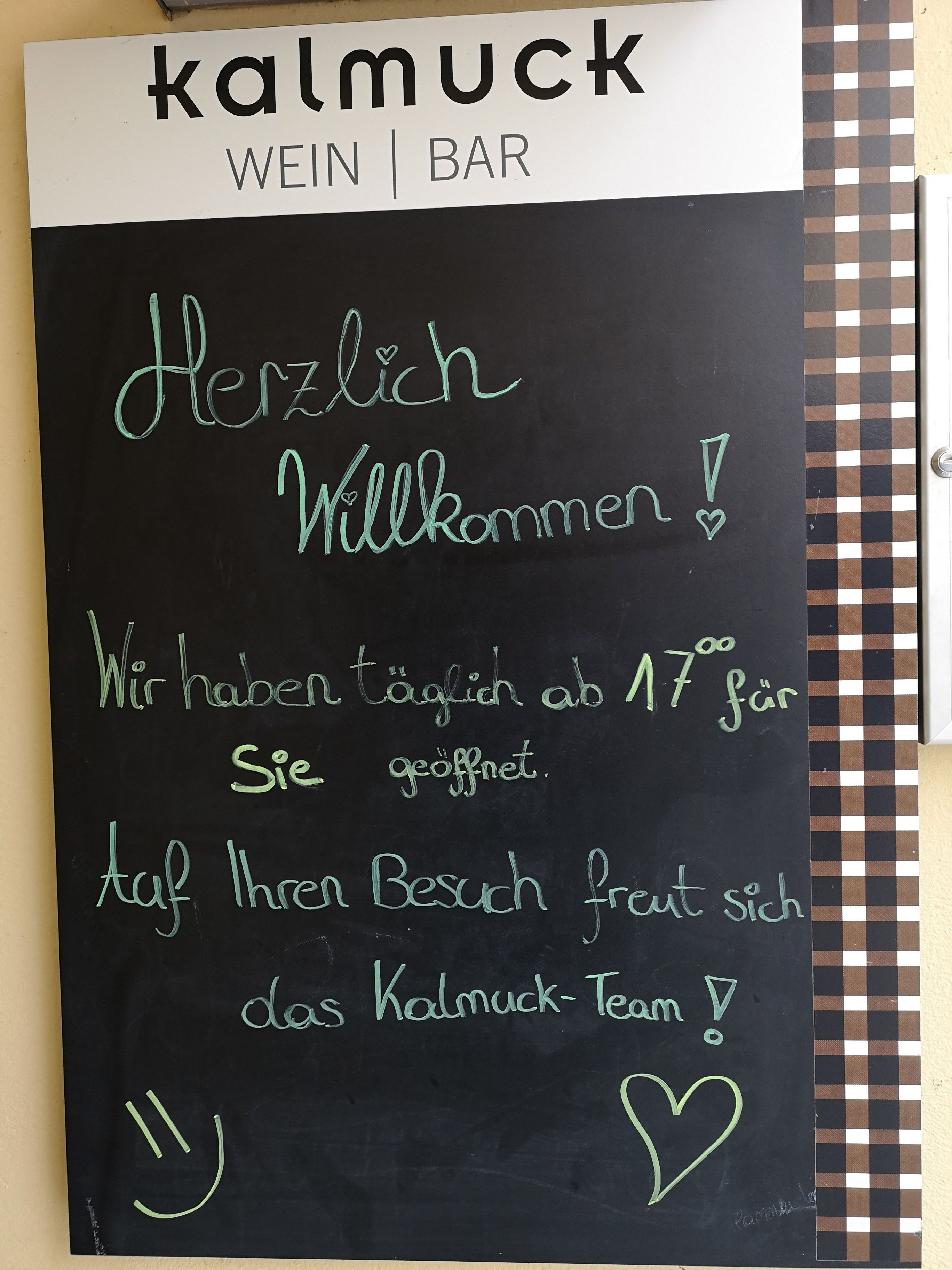 Plaque with welcoming text in front of a wine bar called Kalmuck.
