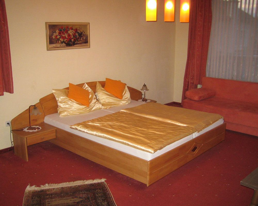 Cozy hotel room with double bed, orange pillows and ceiling lights.