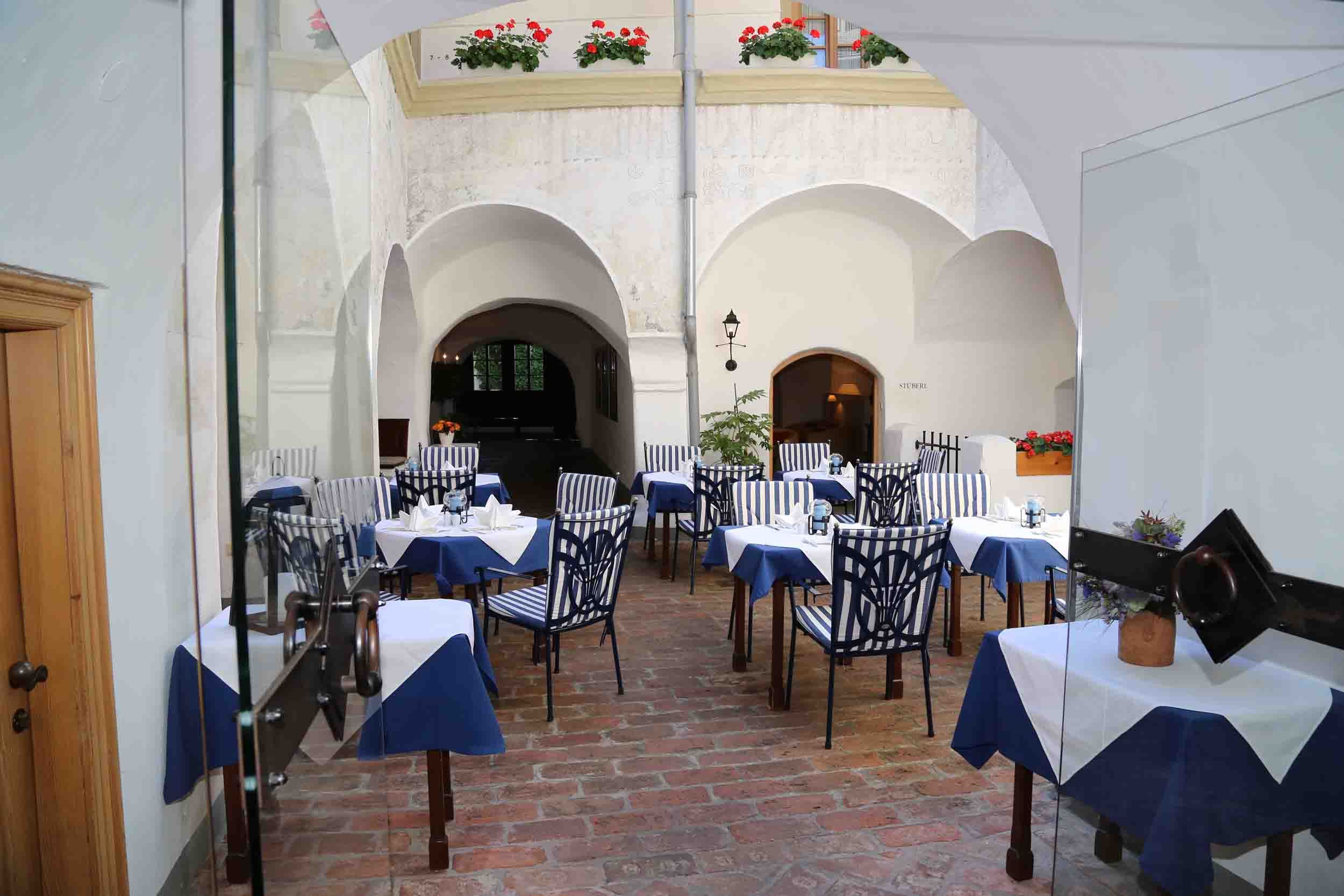 Inner courtyard of a restaurant with laid tables and striped chairs.
