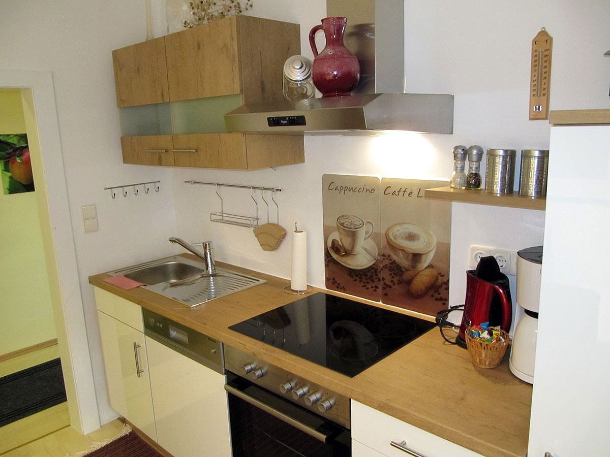Modern kitchen with wooden worktop, stove, sink and coffee machine.