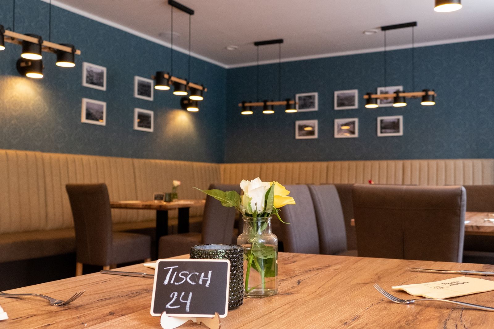 Interior view of a restaurant with wooden table, flowers and modern lighting.