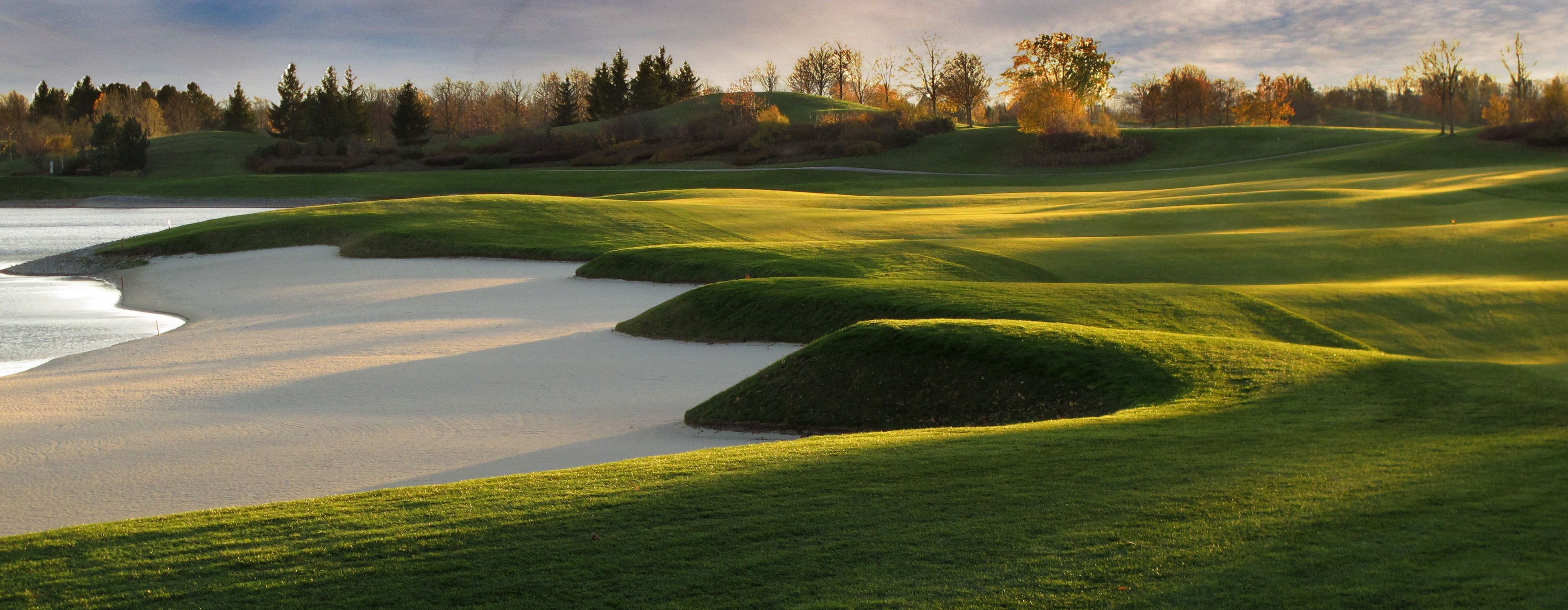 Panorama of a golf course with sand bunkers and green hills in the sunlight.