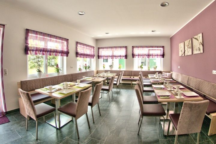 A modern dining room with laid tables, purple curtains and wall decorations.