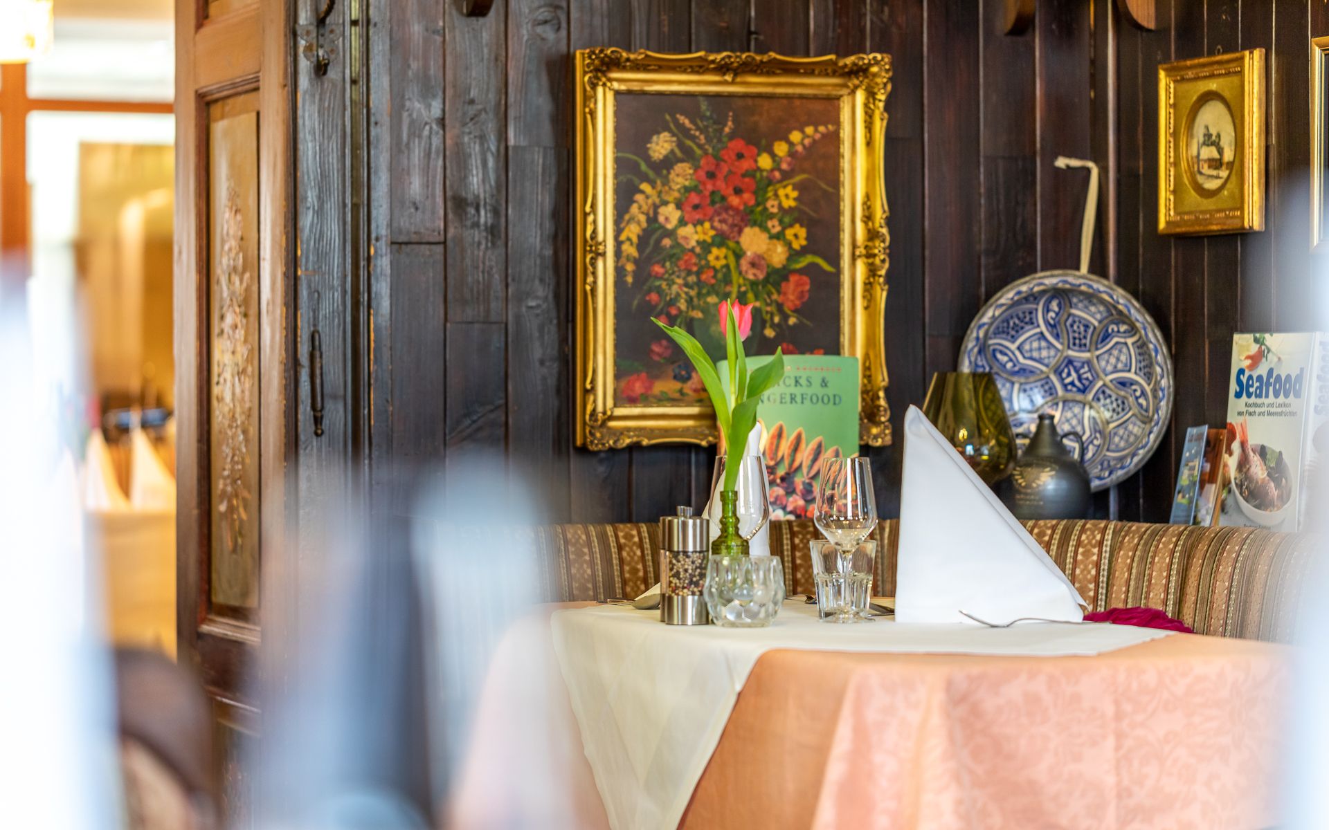 A cozy table setting in a rustic restaurant with a picture of flowers and decorations on the wall.