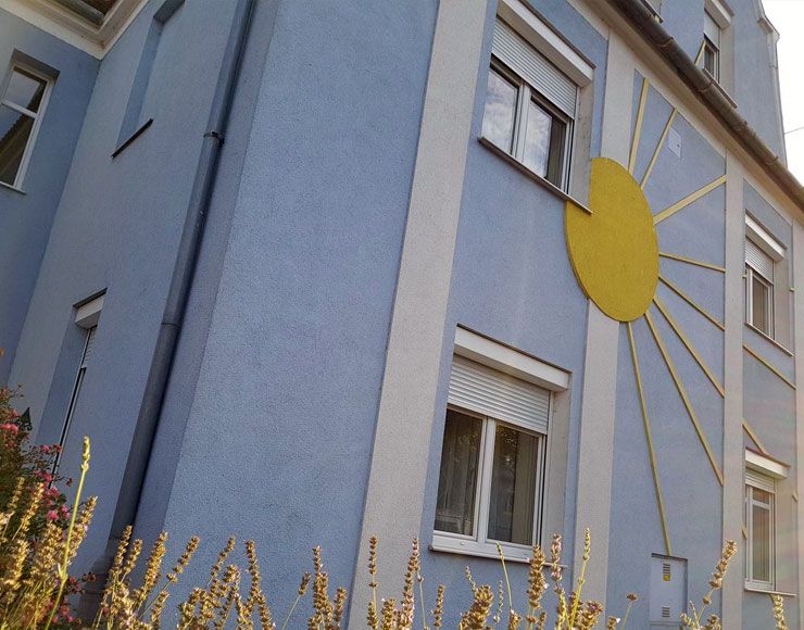 Blue house with yellow sun decoration on the façade.