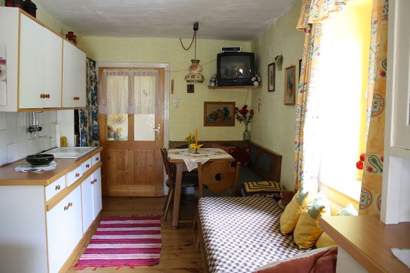 Cozy kitchen in a vacation apartment with wooden furniture, small dining table and TV.