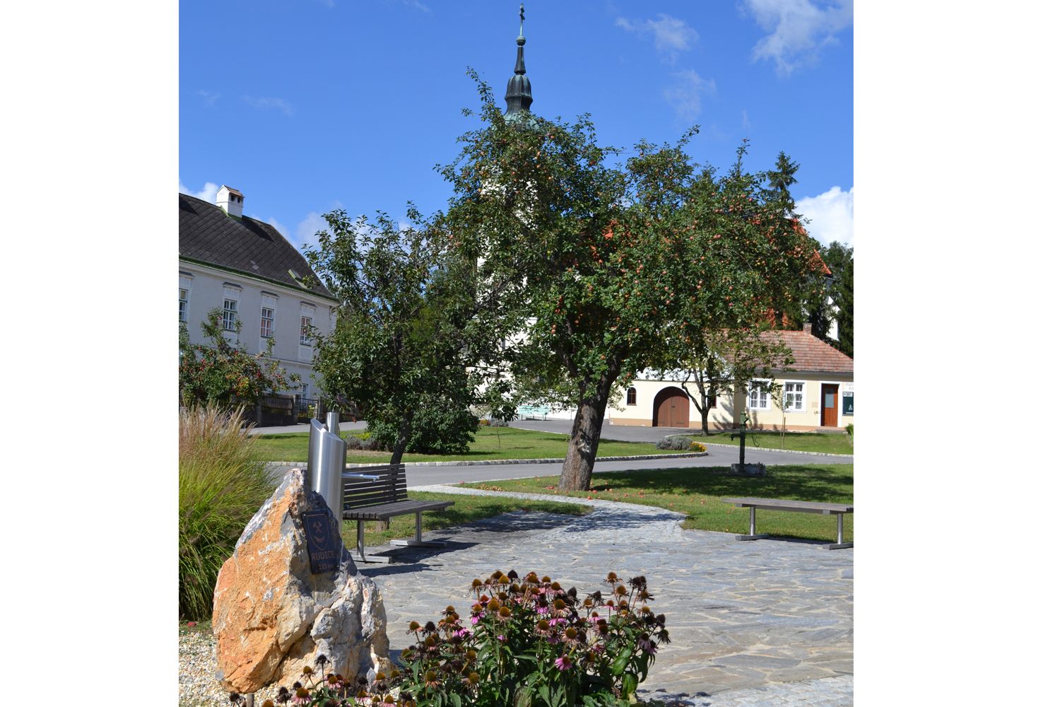 Village square in Hagenberg with church, trees and benches.