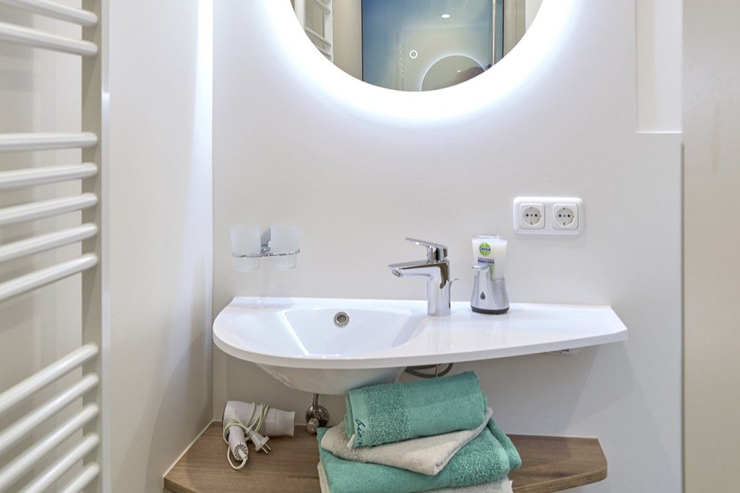 Modern bathroom with round mirror, washbasin and towels.