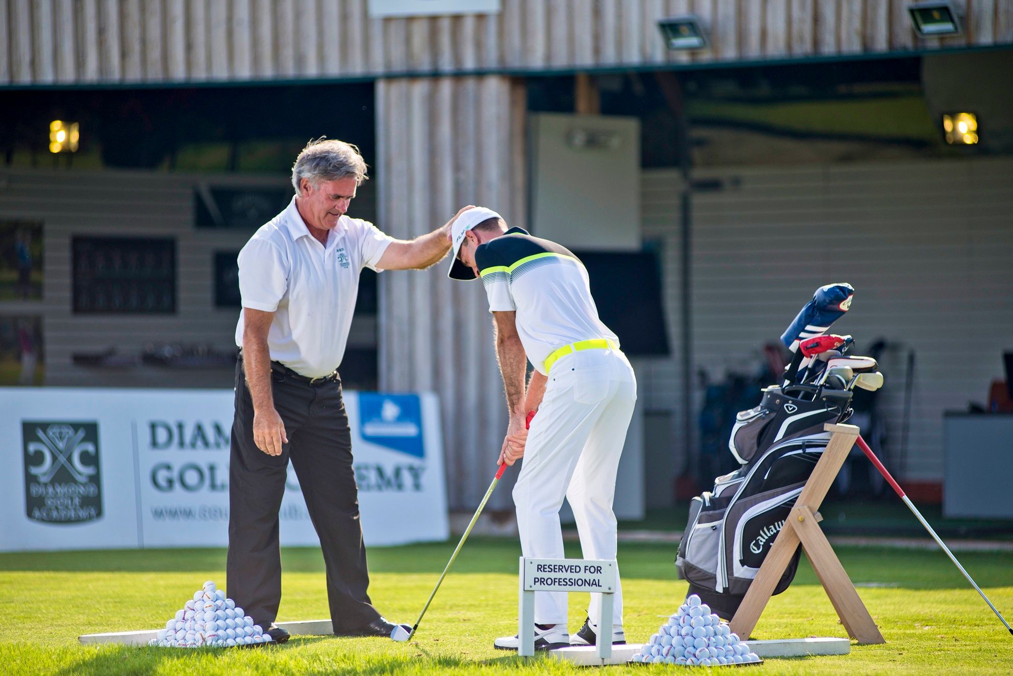 A golf instructor gives instructions to a student on a practice course at the Diamond Golf Academy.
