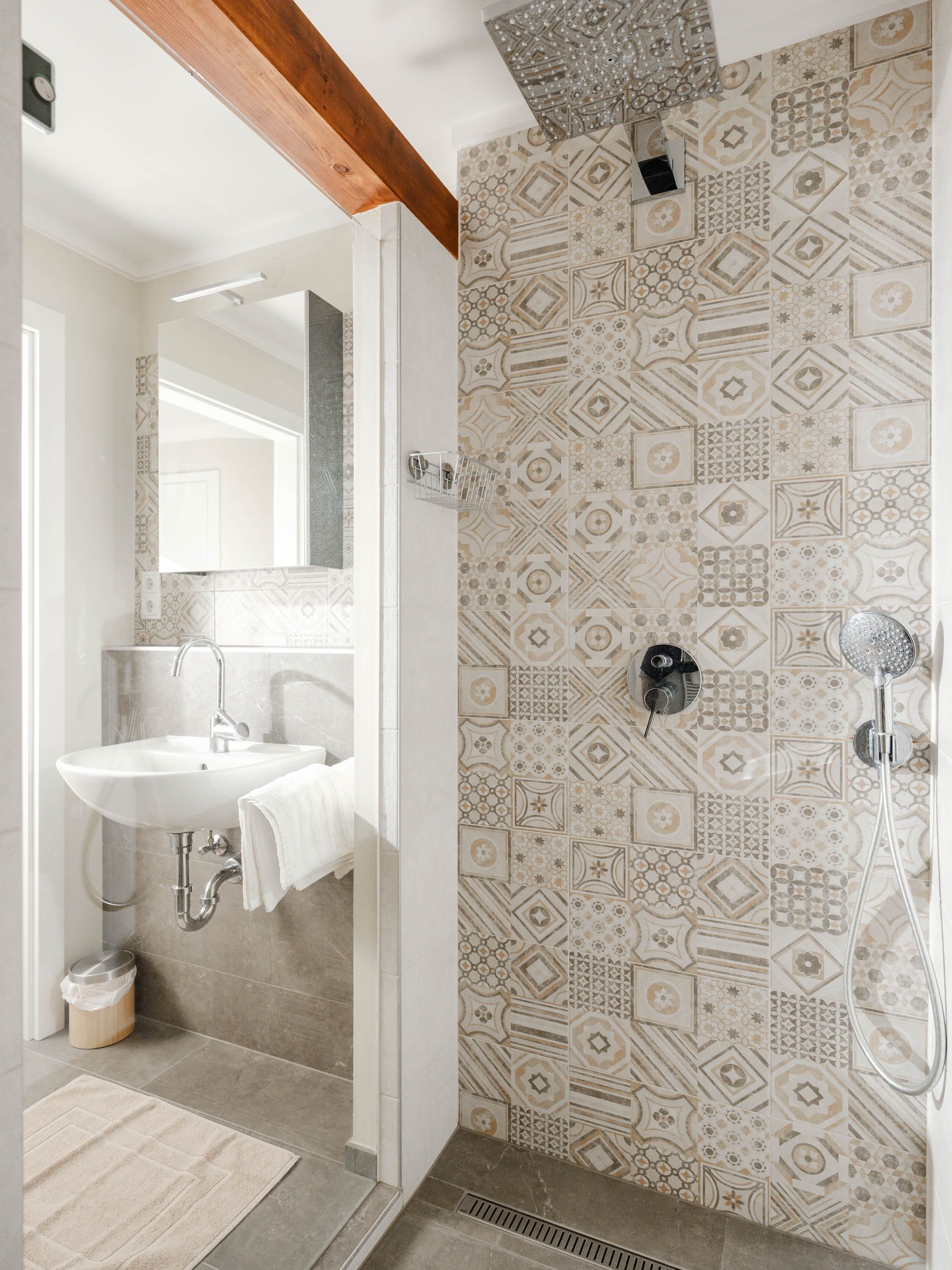Modern bathroom with patterned tiles, washbasin and rain shower.