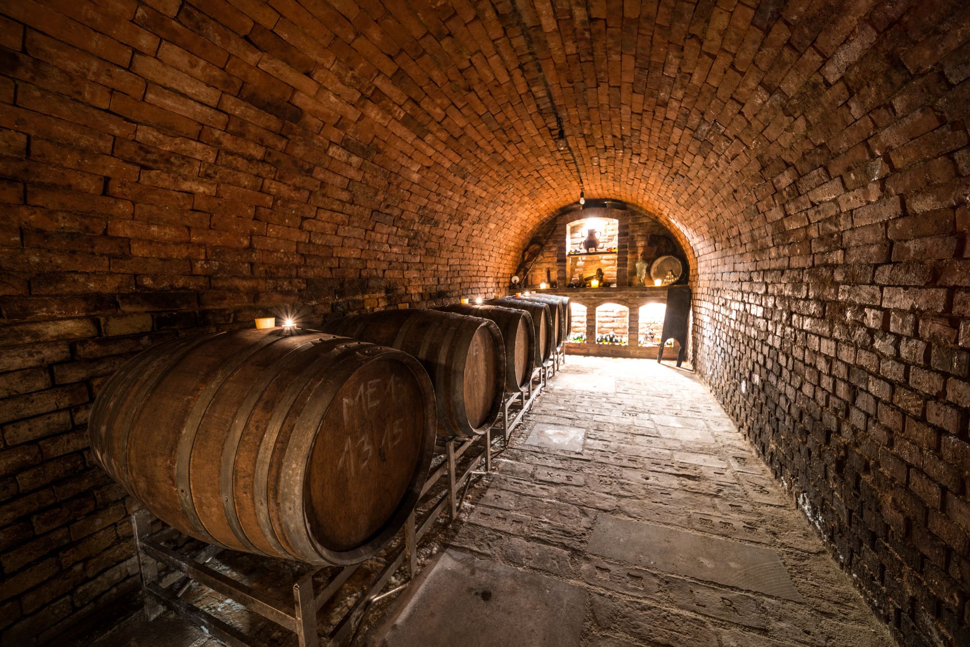 A wine cellar with wooden barrels and brick walls.