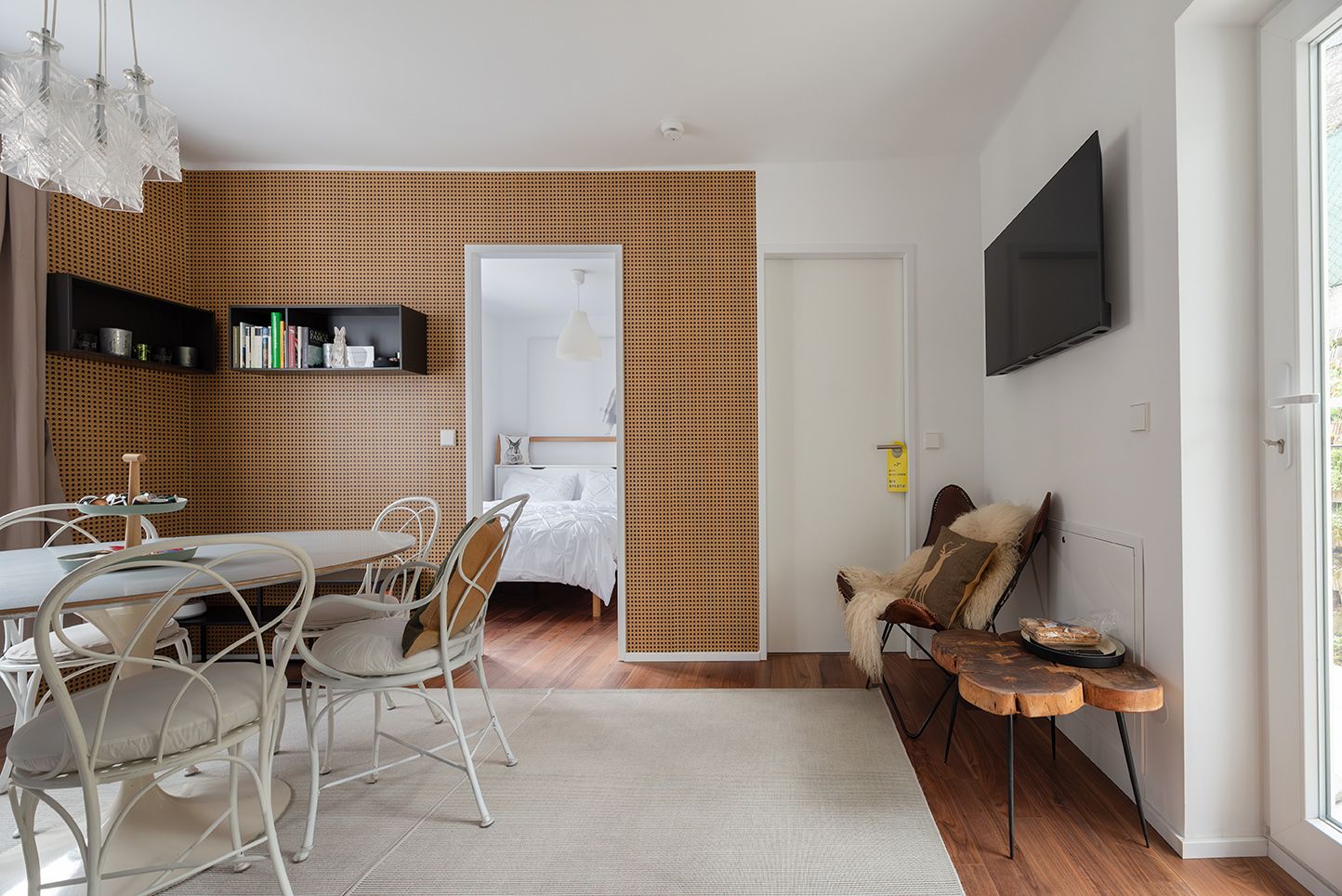 Interior view of a modern furnished living room with dining table, chairs and view into a bedroom.