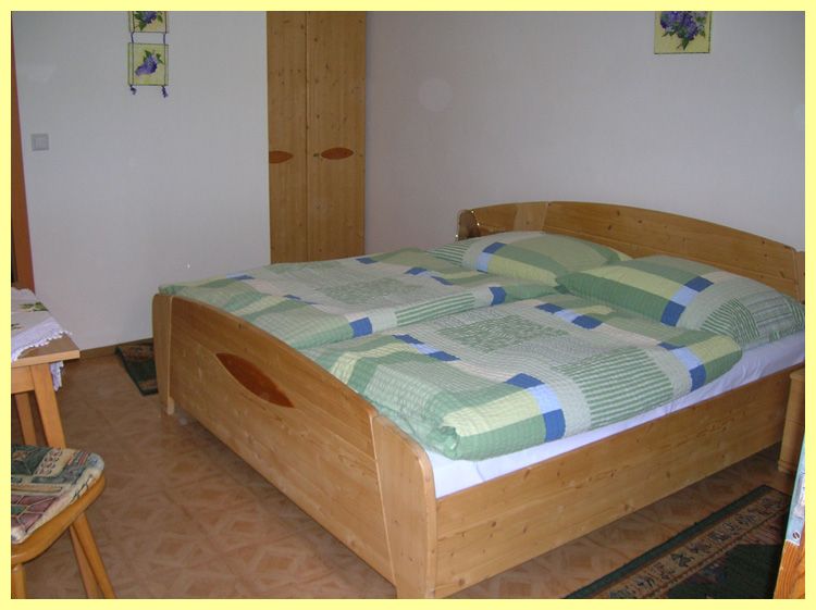 One bedroom with a double bed, wooden furniture and green bed linen.