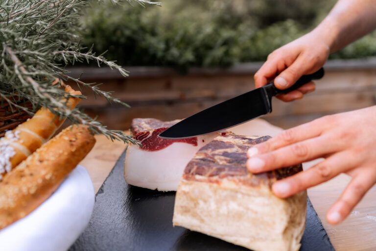 Person cuts bacon on a wooden board.