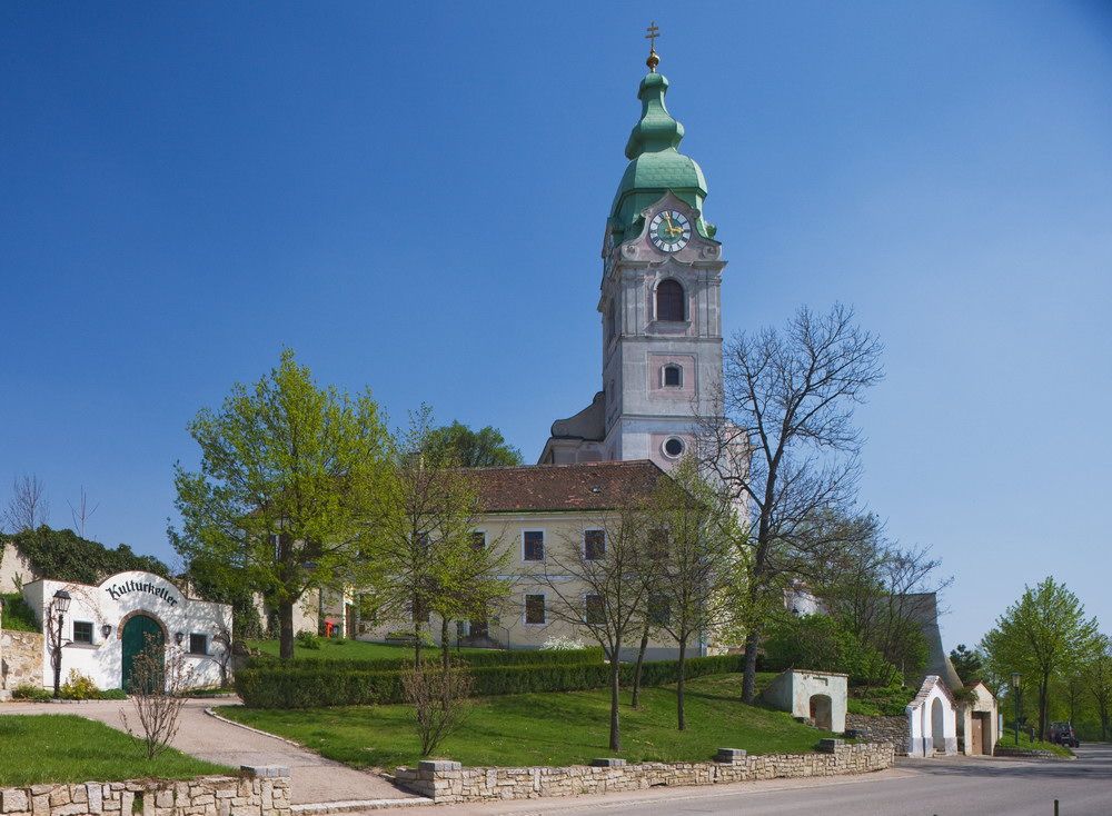 Church in Unterretzbach with green tower and surrounding buildings.
