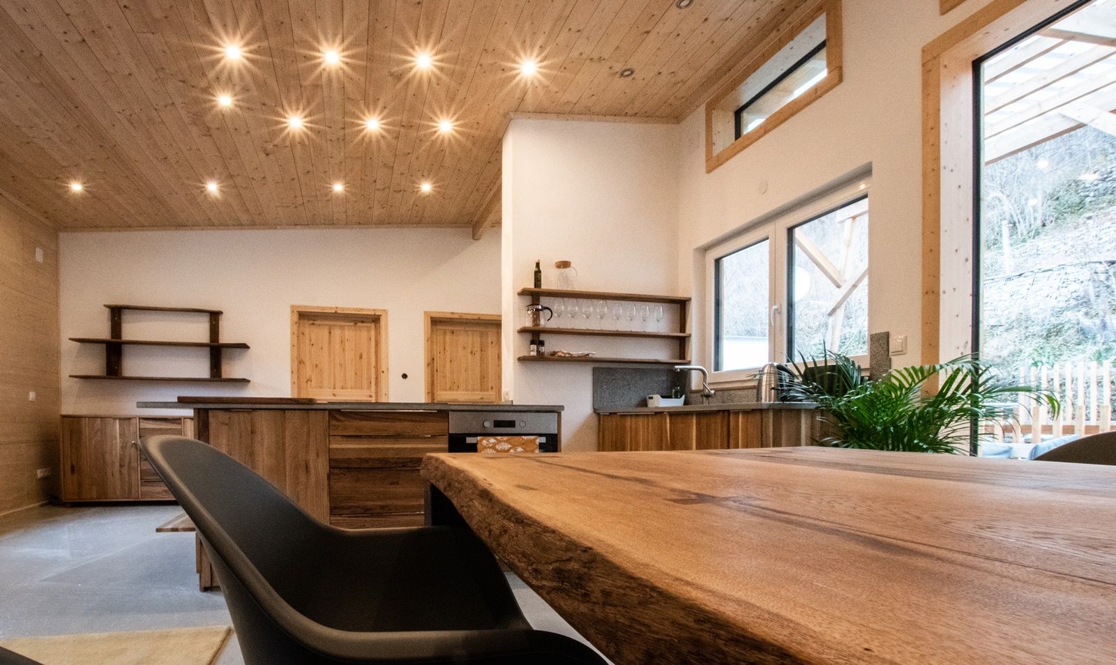 Modern living area with wooden furniture and large windows.