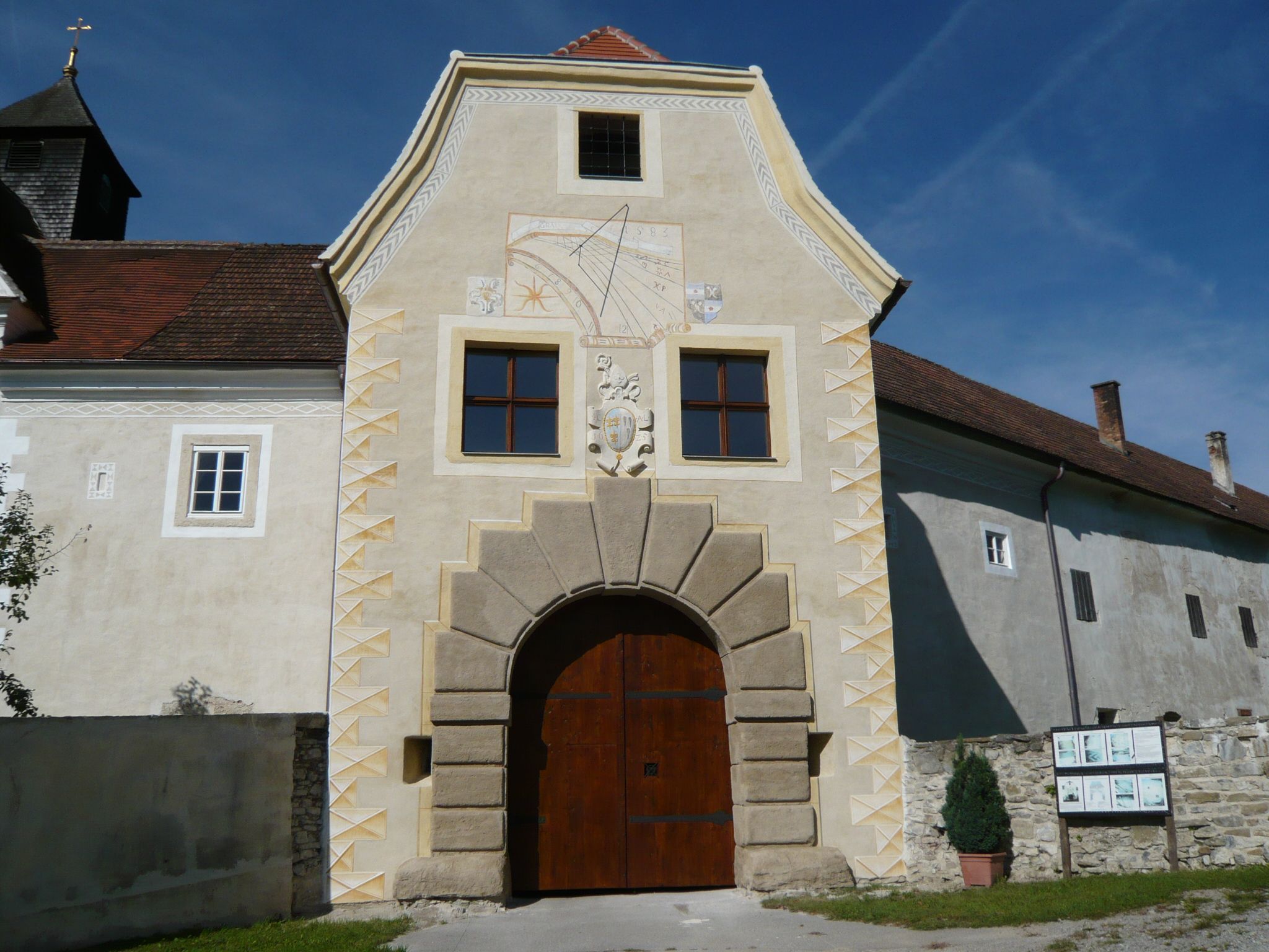 Entrance gate to Kreisbach Castle with sundial and coat of arms.