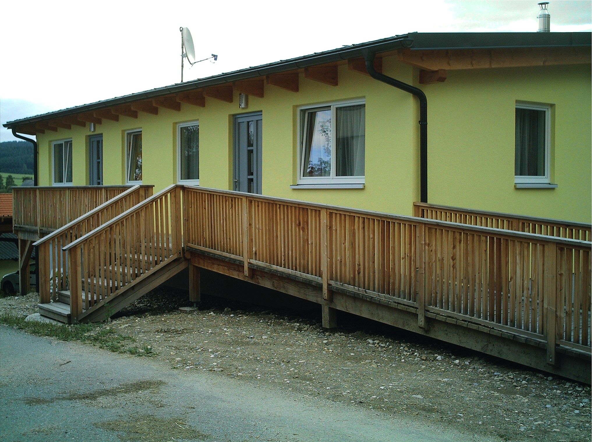 Yellow building with wooden ramp and windows.