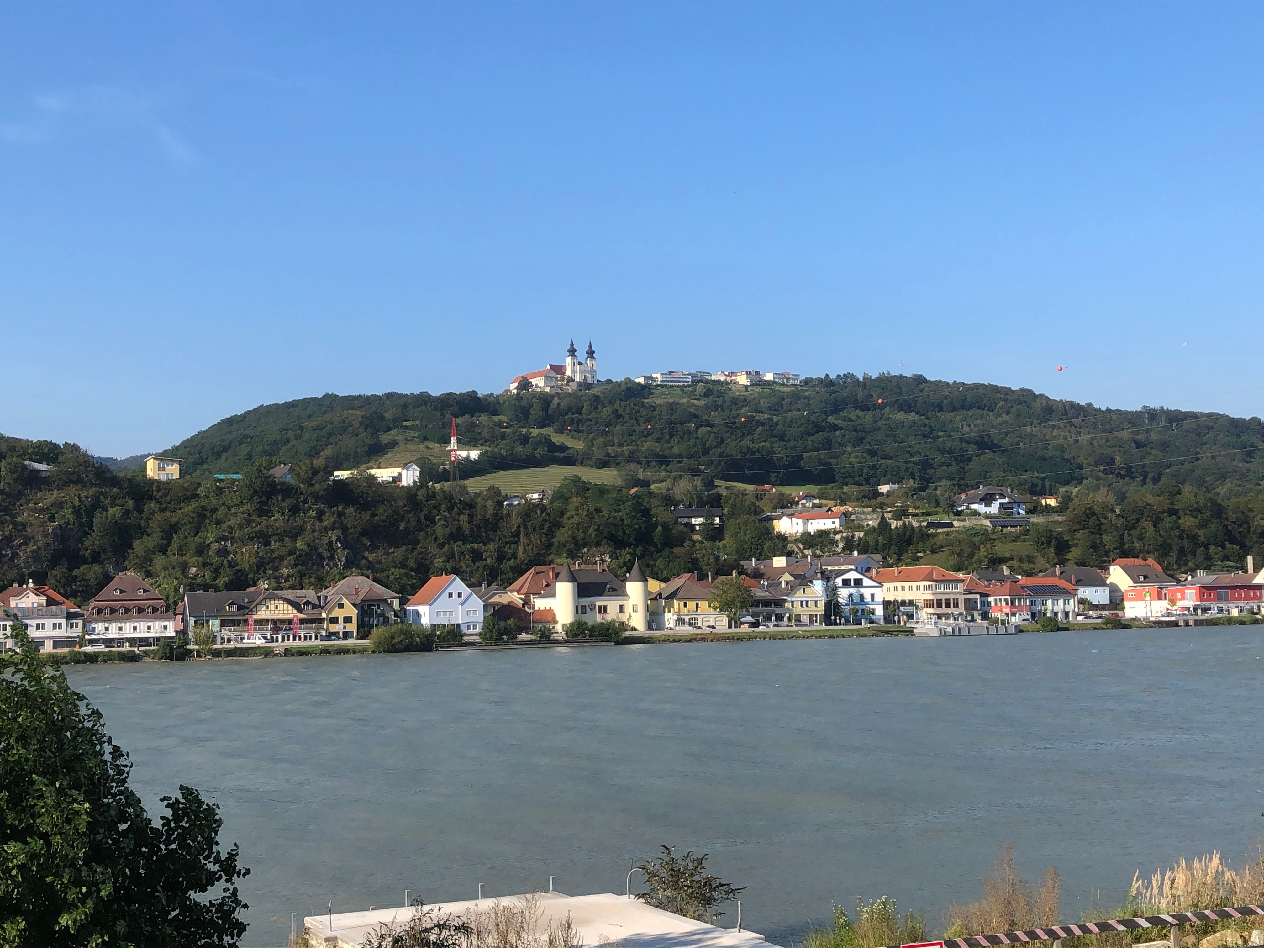 View of the Maria Taferl basilica on a hill, with houses and a river in the foreground.
