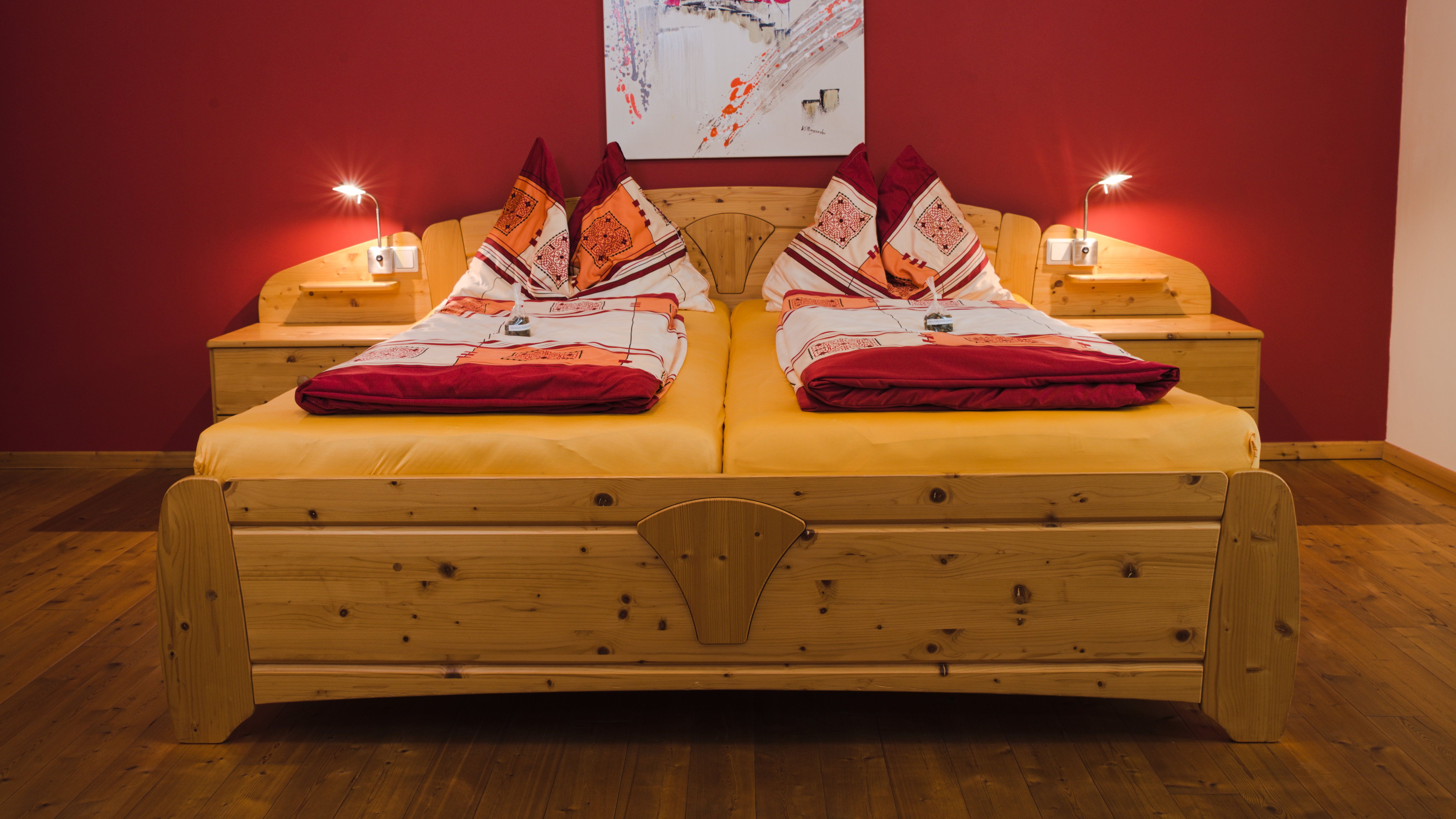 Comfortable double bed with red wall and wooden floor.