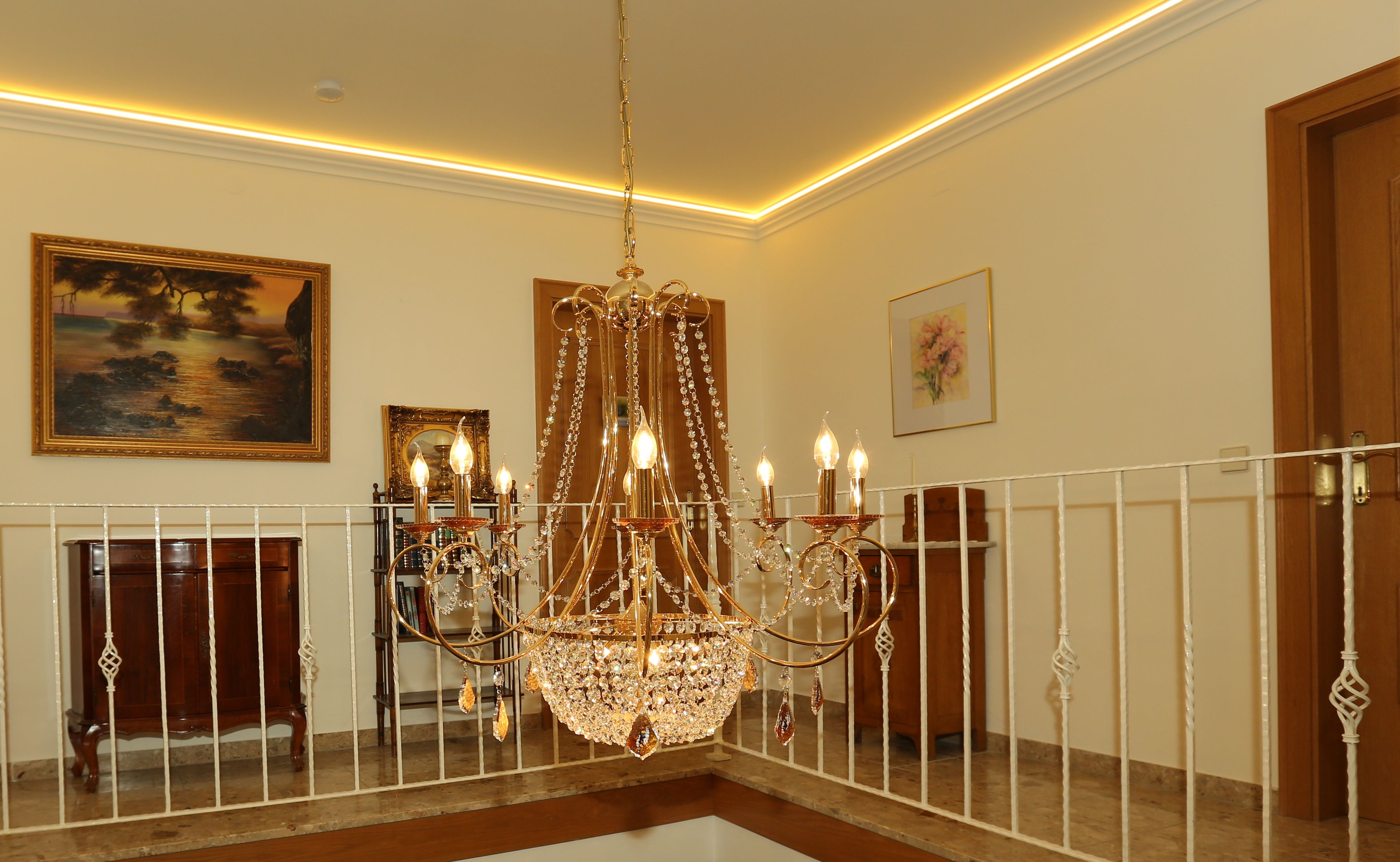 Elegant chandelier in a stylish room with paintings and furniture.
