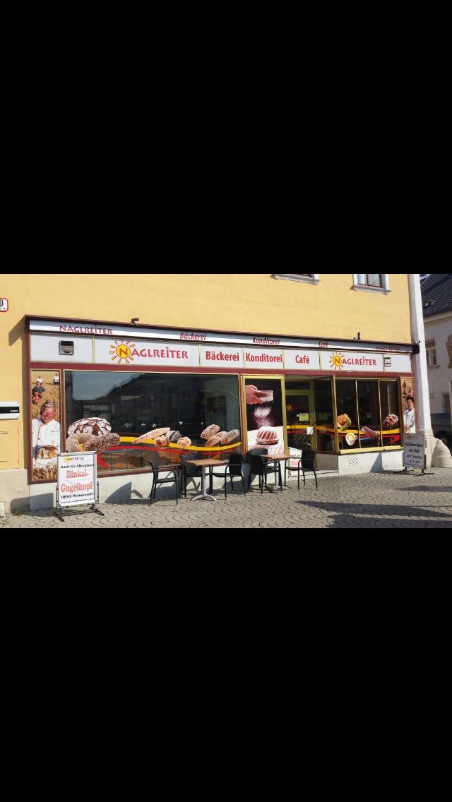 Exterior view of Café-Bäckerei Naglreiter with tables and chairs in front of the store.